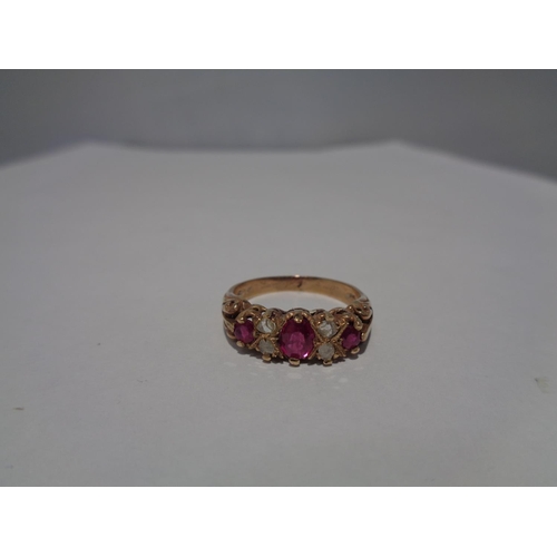 614 - A 9 CARAT GOLD RING WITH THREE IN LINE RUBYS AND FOUR DIAMONDS SIZE P WITH A PRESENTATION BOX