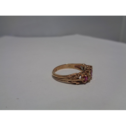 614 - A 9 CARAT GOLD RING WITH THREE IN LINE RUBYS AND FOUR DIAMONDS SIZE P WITH A PRESENTATION BOX