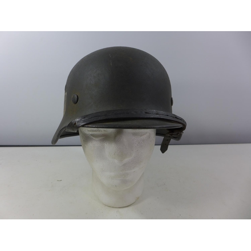 338 - A GERMAN GREEN PAINTED METAL HELMET WITH SS RUNES DECAL AND HAVING BROWN LEATHER LINING