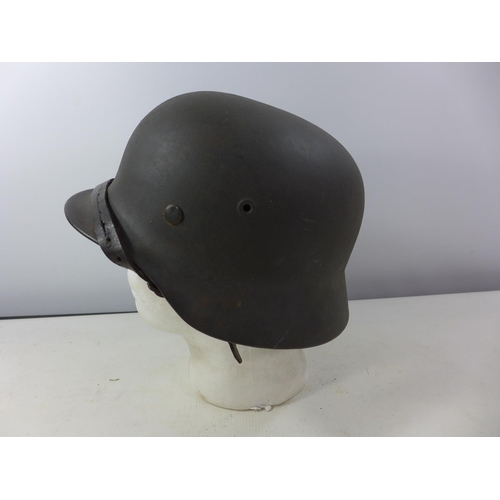 338 - A GERMAN GREEN PAINTED METAL HELMET WITH SS RUNES DECAL AND HAVING BROWN LEATHER LINING