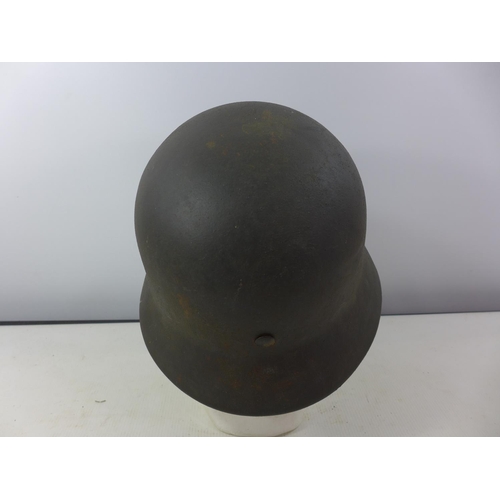 338 - A GERMAN GREEN PAINTED METAL HELMET WITH SS RUNES DECAL AND HAVING BROWN LEATHER LINING