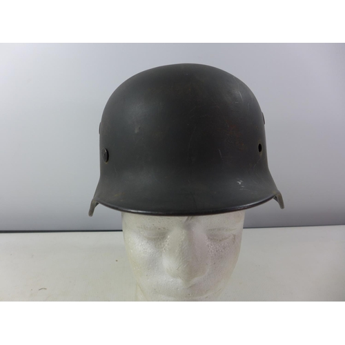 339 - A GERMAN GREEN PAINTED METAL HELMET WITH SS RUNES AND SWASTIKA DECALS AND HAVING BROWN LEATHER LININ... 