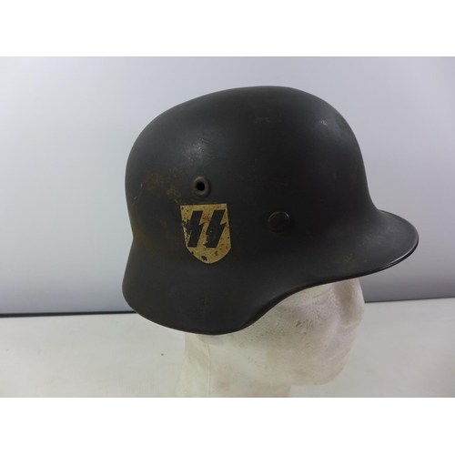 339 - A GERMAN GREEN PAINTED METAL HELMET WITH SS RUNES AND SWASTIKA DECALS AND HAVING BROWN LEATHER LININ... 