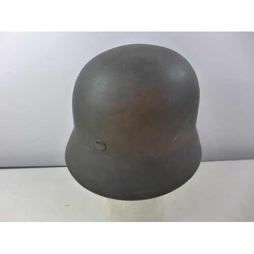 339 - A GERMAN GREEN PAINTED METAL HELMET WITH SS RUNES AND SWASTIKA DECALS AND HAVING BROWN LEATHER LININ... 