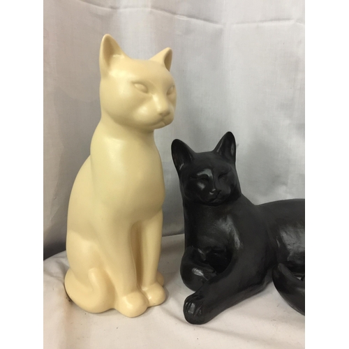 62 - TWO LARGE CAT FIGURES, ONE BLACK, LYING DOWN, LENGTH 36CM, AND A CREAM , HEIGHT 30CM