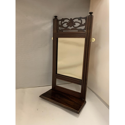 98 - A WOODEN WALL MIRROR WITH A DECORATIVE TOP AND A SHELF