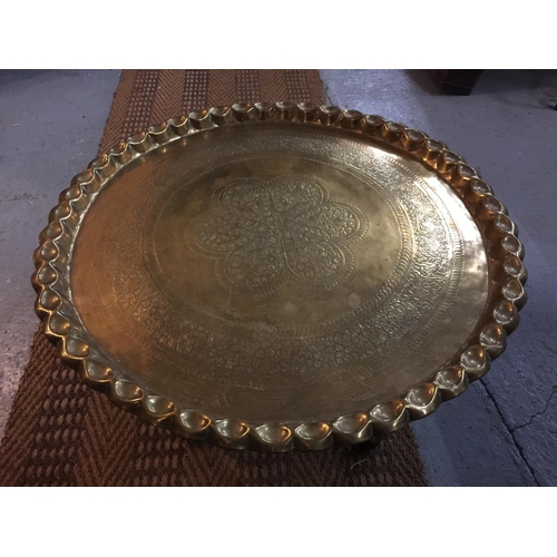 96A - A LARGE DECORATIVE BRASS CHARGER WITH PIE CRUST EDGING ON WOODEN STAND, DIAMETER 67CM, HEIGHT 42CM