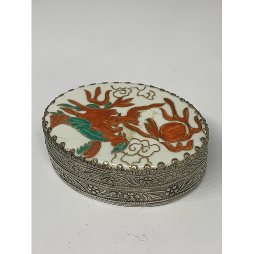 111a - AN ORNATE WHITE METAL BOX WITH INTERNAL MIRROR AND AN ENAMEL LID WITH ORIENTAL DRAGON DESIGN