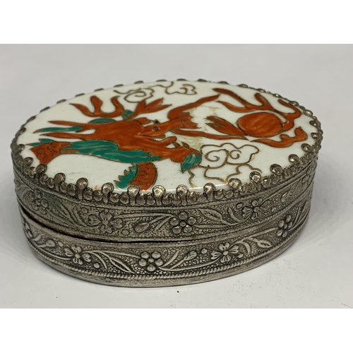 111a - AN ORNATE WHITE METAL BOX WITH INTERNAL MIRROR AND AN ENAMEL LID WITH ORIENTAL DRAGON DESIGN