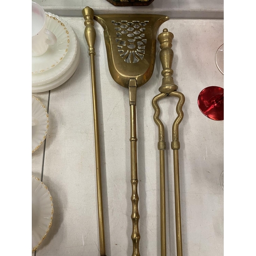 215 - A SET OF BRASS FIRESIDE ITEMS TO INCLUDE, A POKER, TONGS AND A SHOVEL, SIZE 74CM