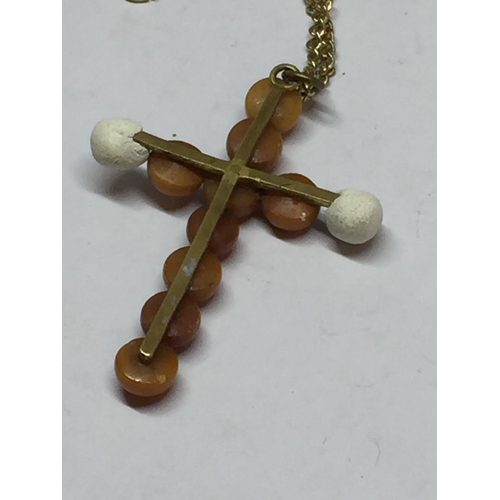 664 - A POSSIBLY BUTTERSCOTCH AMBER CROSS WITH A YELLOW METAL CHAIN