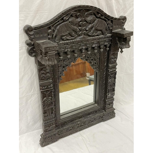 18 - A HEAVILY CARVED EBONY ASIAN STYLE MIRROR WITH ELEPHANT DETAIL 52CM X 79CM