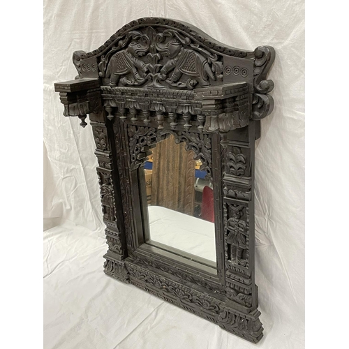 18 - A HEAVILY CARVED EBONY ASIAN STYLE MIRROR WITH ELEPHANT DETAIL 52CM X 79CM