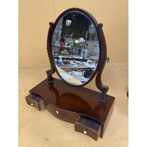 44A - A MAHOGANY OVAL DRESSING TABLE MIRROR WITH A SERPENTINE BOW FRONT CONTAINING ONE LONG AND TWO SHORT ... 