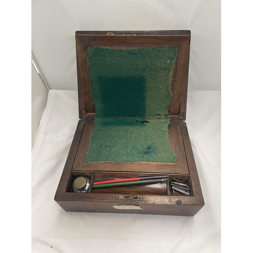 118 - A MAHOGANY WRITING SLOPE CONTAINING AN INKWELL, DIP PENS AND NIBS.  IN NEED OF RESTORATION