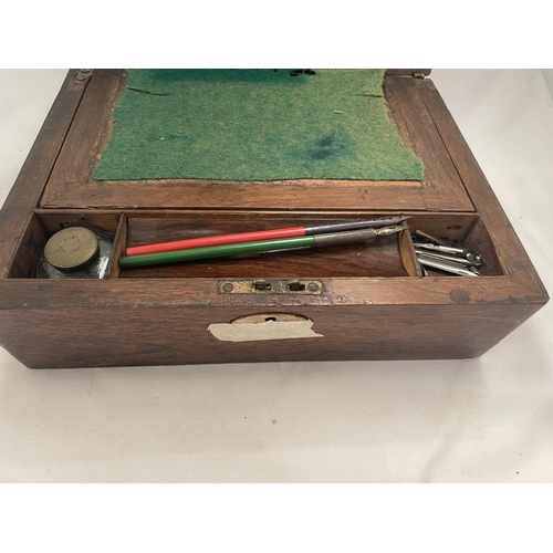 118 - A MAHOGANY WRITING SLOPE CONTAINING AN INKWELL, DIP PENS AND NIBS.  IN NEED OF RESTORATION