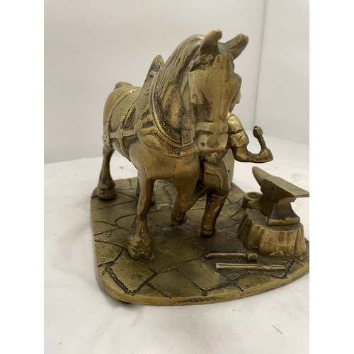 168 - A HEAVY BRASS SHIRE HORSE AT A BLACKSMITHS HEIGHT 18.5CM, WIDTH 20.5CM, LENGTH 24CM