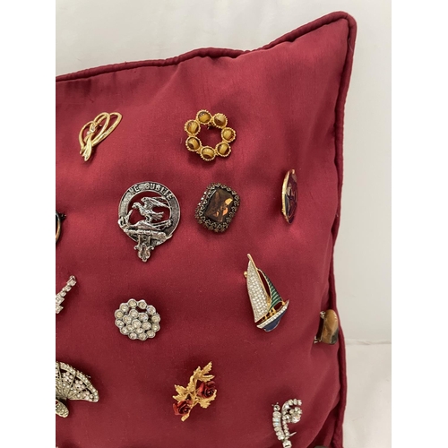 169 - A QUANTITY OF COSTUME JEWELLERY BROOCHES ON A RED CUSHION