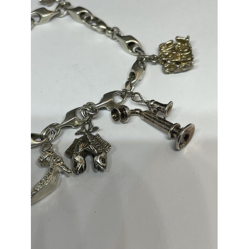 517 - A MARKED SILVER CHARM BRACELET WITH TEN CHARMS TO INCLUDE A HEDGEHOG, SHOE, DOG, TELEPHONE ETC