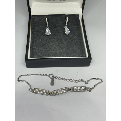 557 - A PAIR OF SILVER AND CLEAR STONE EARRINGS AND A MATCHING BRACELET IN A BOX