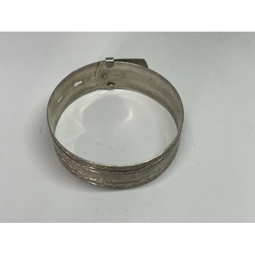 570 - A MARKED SILVER BANGLE IN A BELT DESIGN