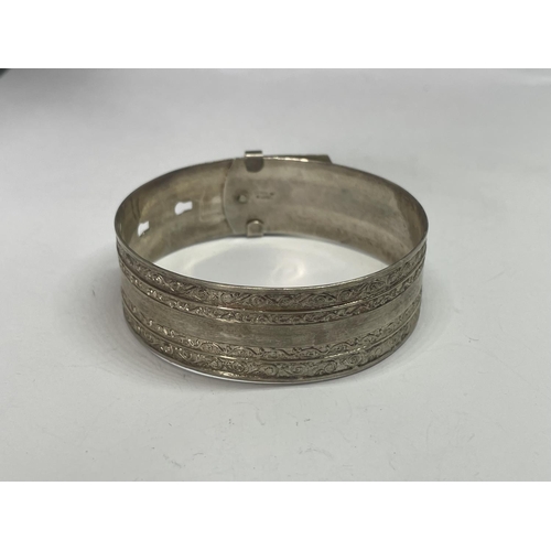 570 - A MARKED SILVER BANGLE IN A BELT DESIGN