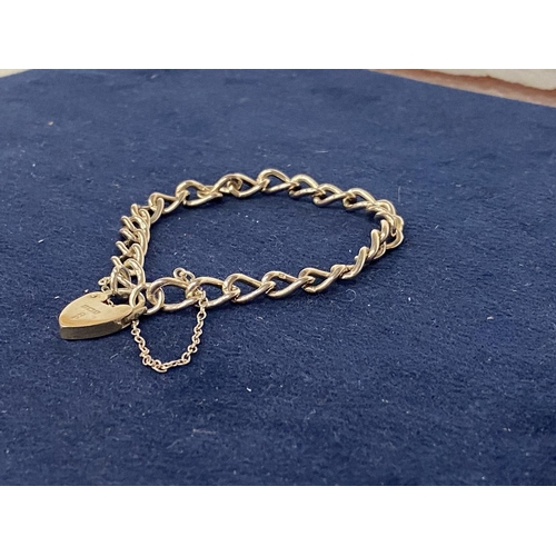 555 - A HALLMARKED SILVER BRACELET WITH A HALLMARKED HEART SHAPED LOCK ON A CURB LINK BRACELET