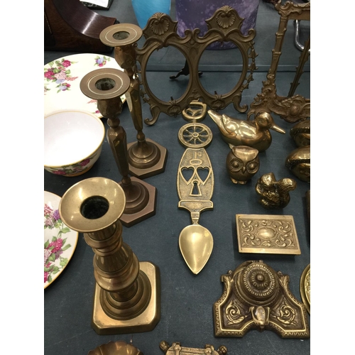 65 - A LARGE QUANTITY OF BRASSWARE TO INCLUDE CANDLESTICKS, INKWELLS, PHOTO FRAMES, ANIMALS, TRINKET BOXE... 