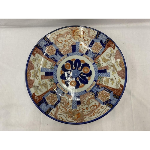 21 - A LARGE IMARI CHARGER WITH HAND PAINTED PANELS RED AND BLUE PATTERNS AND STORKS TO THE RIM, DIAMETER... 