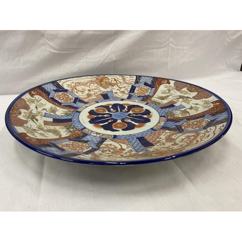 21 - A LARGE IMARI CHARGER WITH HAND PAINTED PANELS RED AND BLUE PATTERNS AND STORKS TO THE RIM, DIAMETER... 