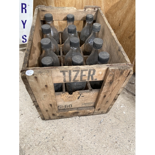 1211 - A VINTAGE WOODEN MONOGRAMED TIZER CRATE CONTAINING 12 VINTAGE GLASS TIZER BOTTLES