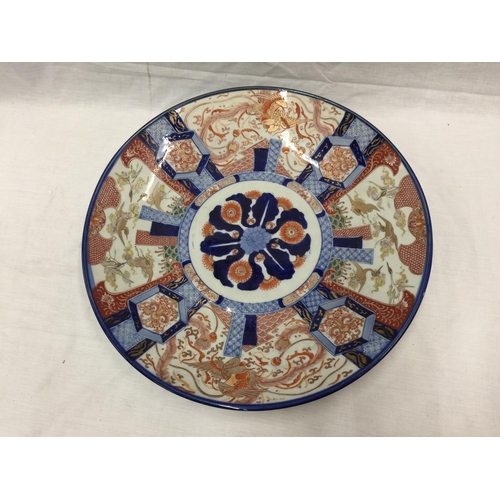 21 - A LARGE IMARI CHARGER WITH HAND PAINTED PANELS RED AND BLUE PATTERNS AND STORKS TO THE RIM, DIAMETER... 