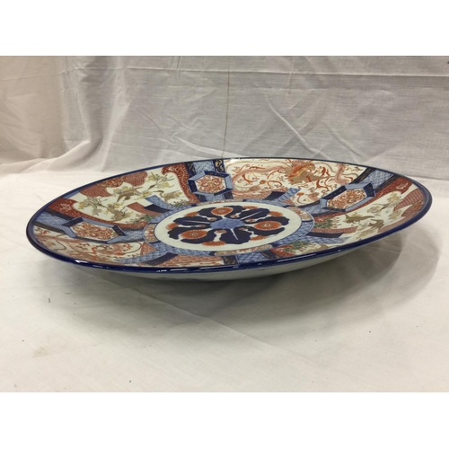 21 - A LARGE IMARI CHARGER WITH HAND PAINTED PANELS RED AND BLUE PATTERNS AND STORKS TO THE RIM, DIAMETER... 