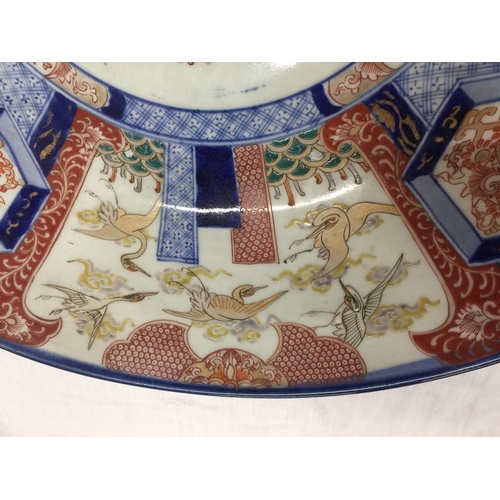 21 - A LARGE IMARI CHARGER WITH HAND PAINTED PANELS RED AND BLUE PATTERNS AND STORKS TO THE RIM, DIAMETER... 