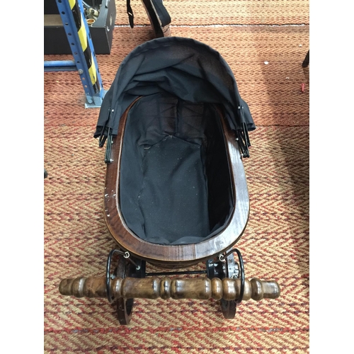 234 - A VINTAGE STYLE  WOODEN DOLL'S PRAM WITH METAL SUSPENSION, A HOOD AND BLACK FITTED INTERIOR