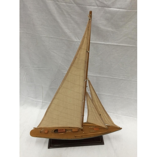 320 - A MODEL OF A HAND PAINTED SINGLE MASTED SAILING SHIP ON A STAND L: 61CM