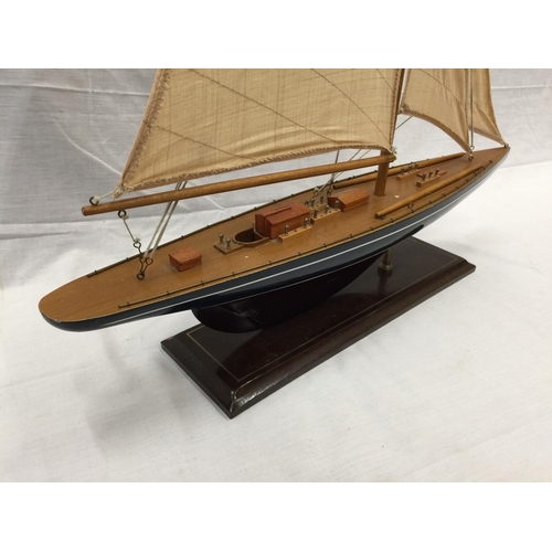 320 - A MODEL OF A HAND PAINTED SINGLE MASTED SAILING SHIP ON A STAND L: 61CM