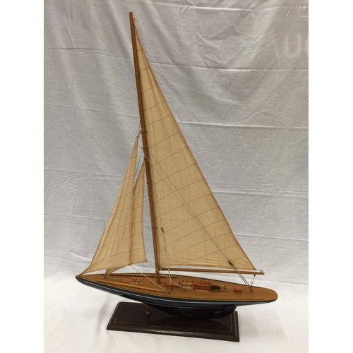 320 - A MODEL OF A HAND PAINTED SINGLE MASTED SAILING SHIP ON A STAND L: 61CM