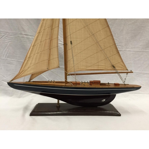 320 - A MODEL OF A HAND PAINTED SINGLE MASTED SAILING SHIP ON A STAND L: 61CM