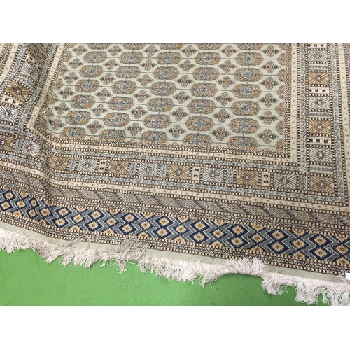 933 - A LARGE FRINGED RUG IN BEIGE, PALE GREEN AND NAVY