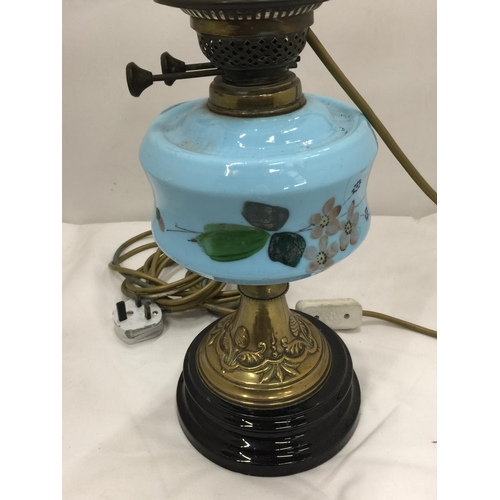 50 - A CONVERTED VINTAGE BRASS OIL LAMP ON BRASS STAND AND SOLID HEAVY BASE WITH PAINTED CERAMIC DECORATI... 