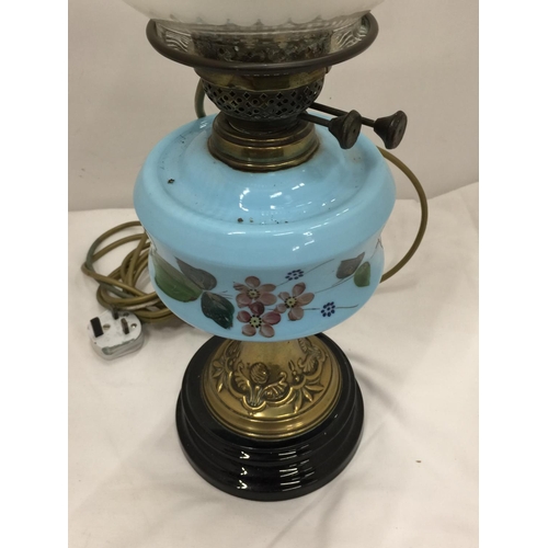 50 - A CONVERTED VINTAGE BRASS OIL LAMP ON BRASS STAND AND SOLID HEAVY BASE WITH PAINTED CERAMIC DECORATI... 