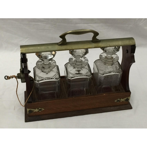 14 - A VINTAGE MAHOGANY AND BRASS TANTALUS WITH THREE MATCHING DECANTERS AND KEY