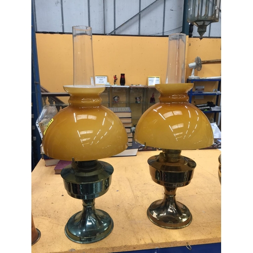 47 - A PAIR OF VINTAGE BRASS OIL LAMPS WITH APRICOT COLOURED GLASS SHADES A/F REPAIRS TO ONE GLASS SHADE