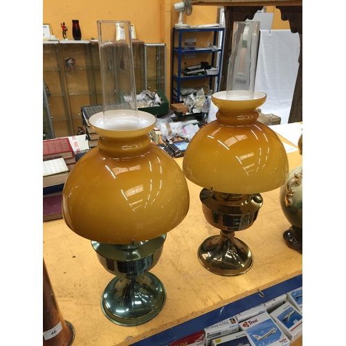 47 - A PAIR OF VINTAGE BRASS OIL LAMPS WITH APRICOT COLOURED GLASS SHADES A/F REPAIRS TO ONE GLASS SHADE