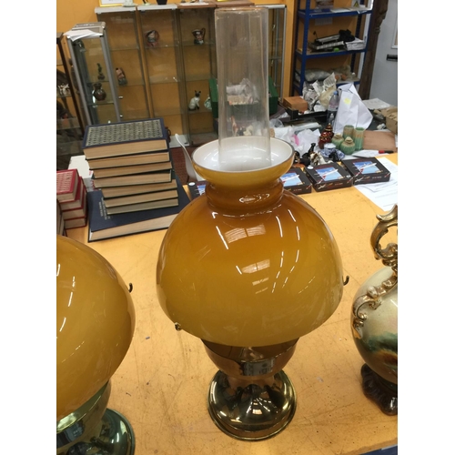 47 - A PAIR OF VINTAGE BRASS OIL LAMPS WITH APRICOT COLOURED GLASS SHADES A/F REPAIRS TO ONE GLASS SHADE