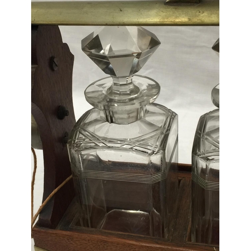 14 - A VINTAGE MAHOGANY AND BRASS TANTALUS WITH THREE MATCHING DECANTERS AND KEY