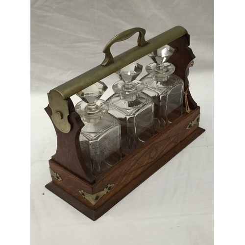 14 - A VINTAGE MAHOGANY AND BRASS TANTALUS WITH THREE MATCHING DECANTERS AND KEY