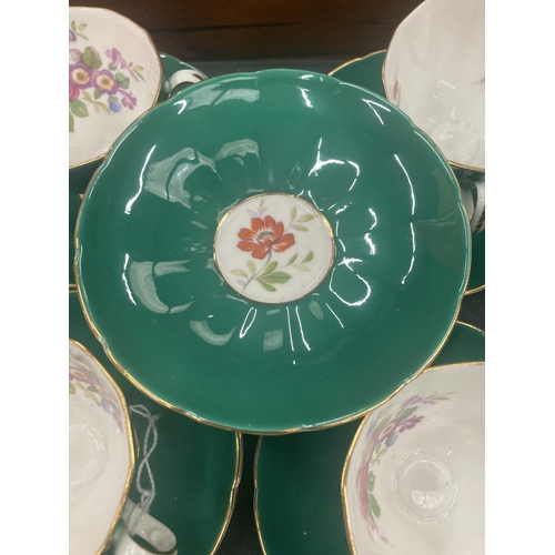 74 - FIVE ADDERLEY CHINA CUPS AND SIX SAUCERS IN A DARK GREEN WITH A FLORAL PATTERN