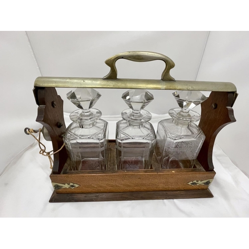 13 - A VINTAGE MAHOGANY AND BRASS TANTALUS WITH THREE MATCHING DECANTERS AND KEY